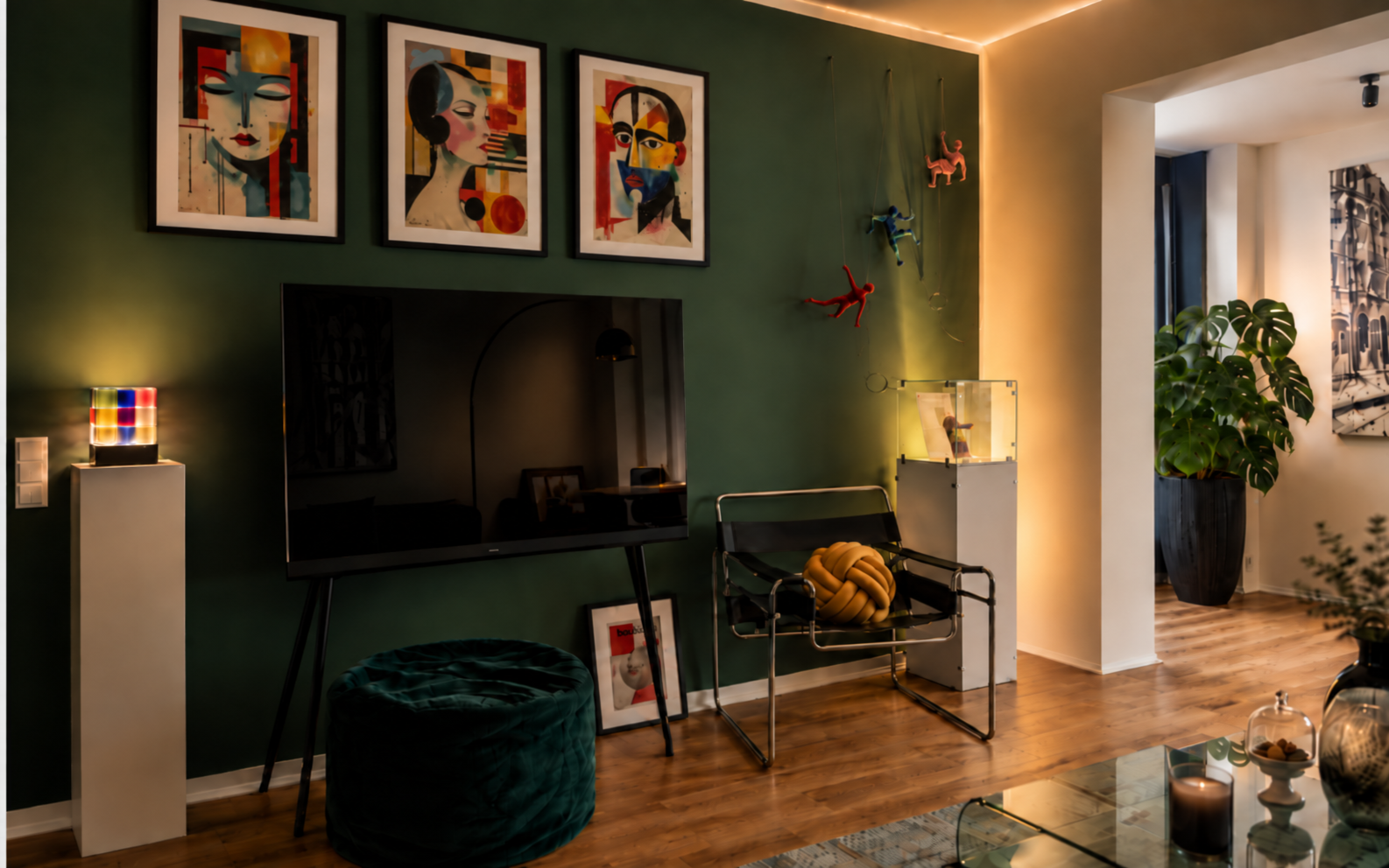 Wohnraum mit grüner Akzentwand, Kunst, Designmöbeln und warmer Lichtstimmung